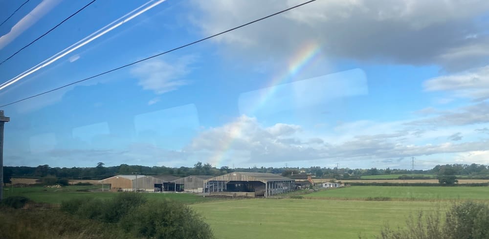 A view of a field with a rainbow over it, somewhere in England