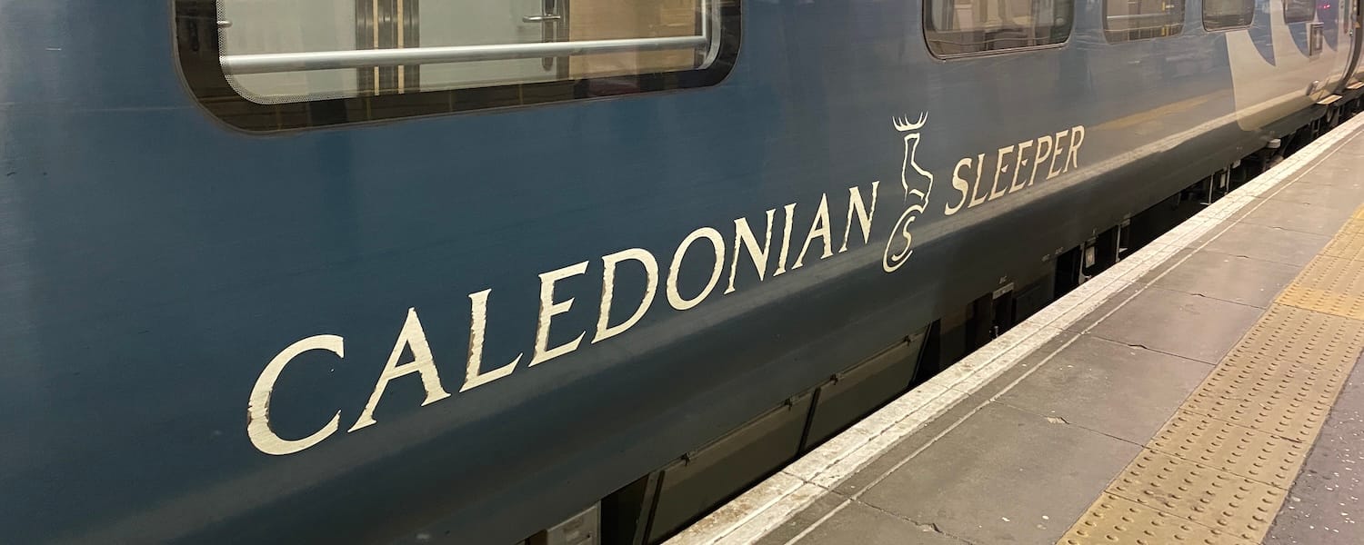 The side of the Caledonian Sleeper train, featuring logo and windows.