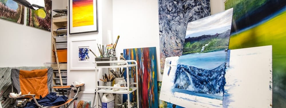 Multicoloured canvases, brushes and paints in a white-walled studio