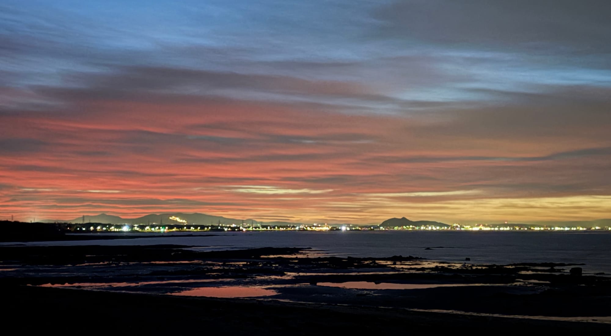 A picture of the Edinburgh skyline with a red sunset behind it, taken from East Lothian