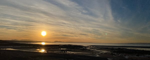 The sun setting over Edinburgh with the sea in the foreground.