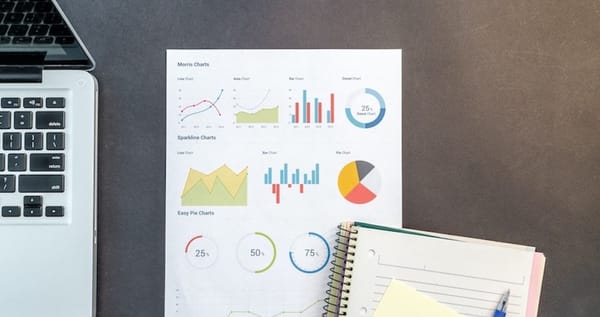 Macbook, notebook, paper with graphs and charts