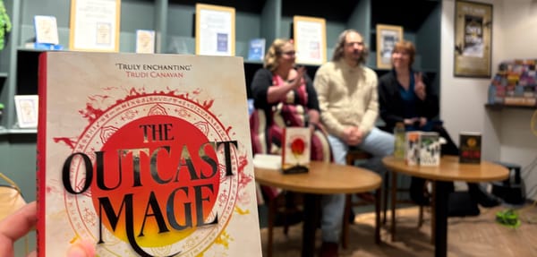 The cover of 'The Outcast Mage' with the attending panel authors in the background.